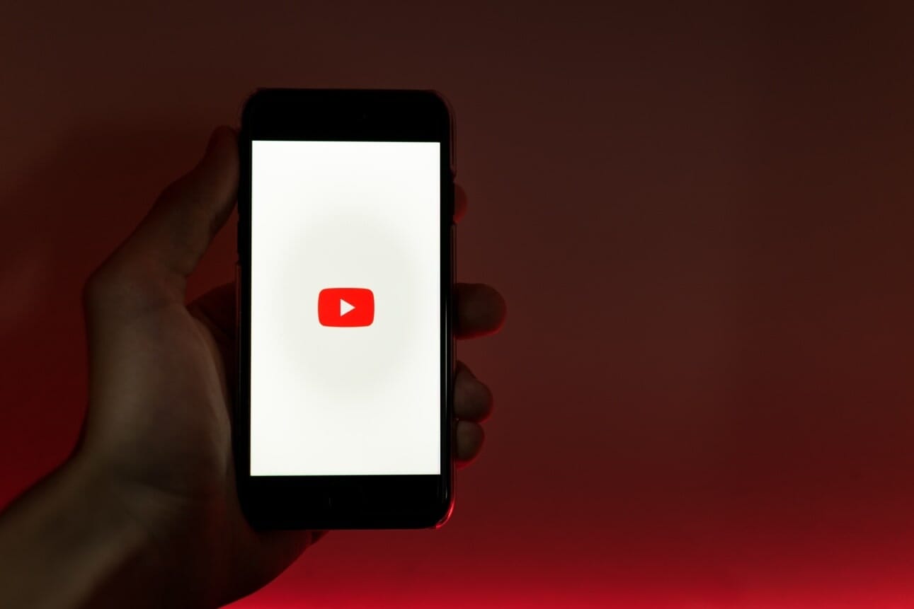person holding smartphone with opened youtube app