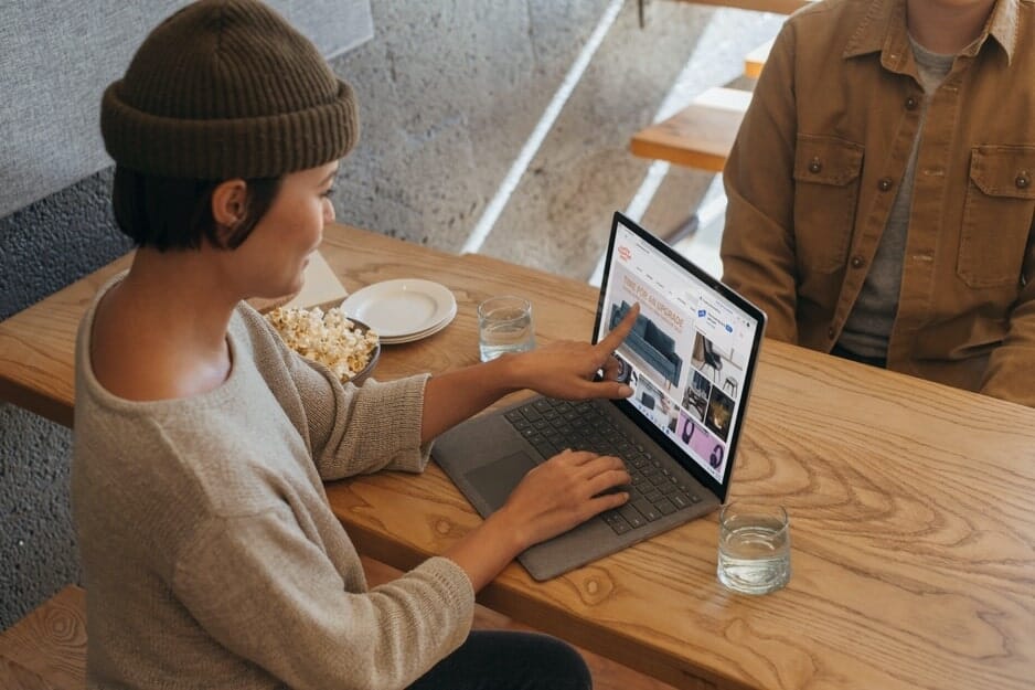 woman wearing a beanie pointing the screen on the laptop